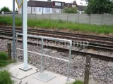 Pedestrian safety handrails fitted by railway track with residential house in the far left 